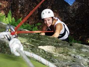 A female Camper rock climbing.