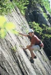 A male Camper rock climbing.
