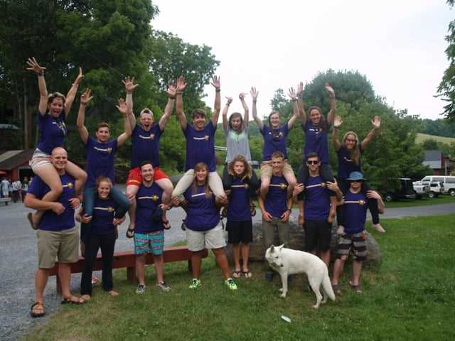 A group of Campers and a canine posing a picture.