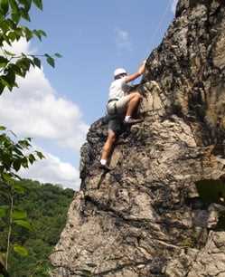 A male Camper rock climbing.