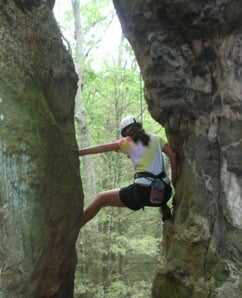 A female Camper rock climbing.