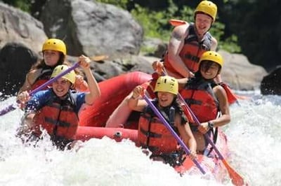 A group of Campers having fun in a white water rafting session.