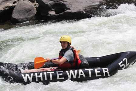 A male camper white water rafting.