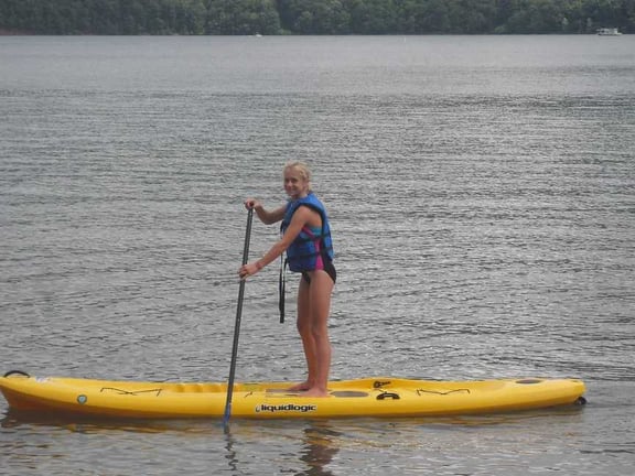 A female Camper doing a stand-up paddle boarding.