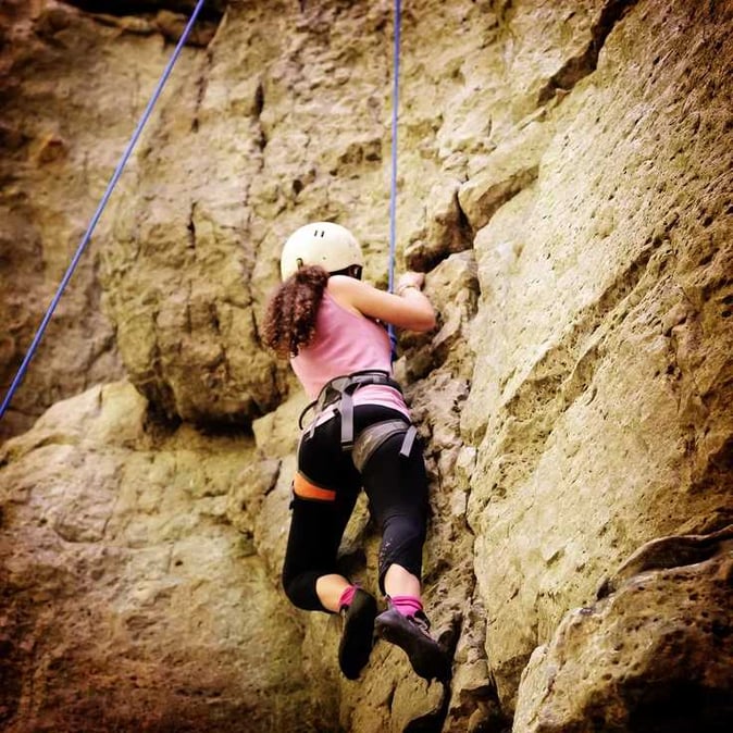A female Camper rock climbing.