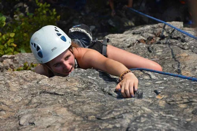 A female Camper rock climbing