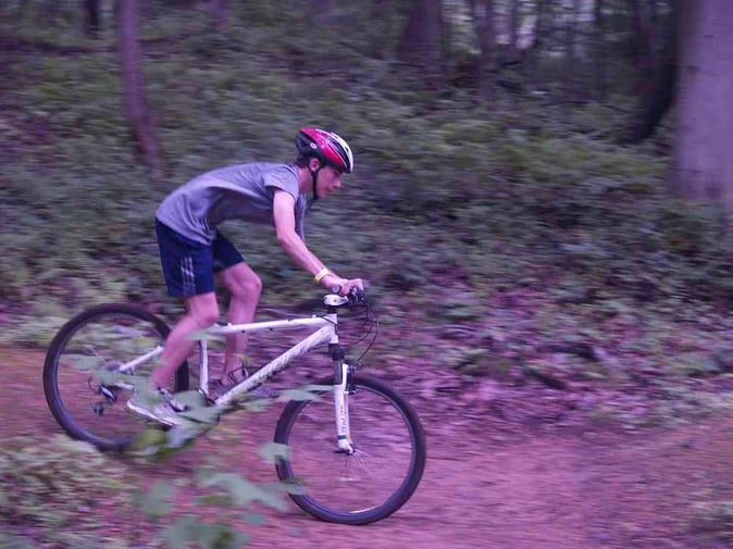 A male Camper with his head up while descending from the mountain with his bike.