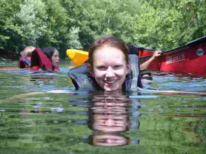 Picture of a female Camper swimming with a life jacket