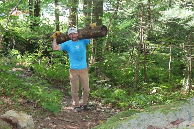 Picture of a staff carrying a log of wood for the trail