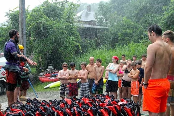 Campers standing in the rain while listening to briefing about white water rafting safety