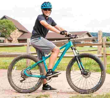 A male Camper pose for a picture on his bike