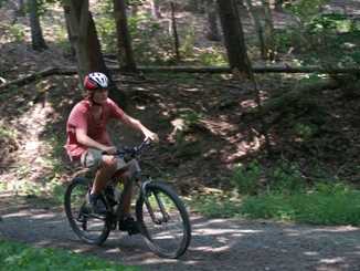 A Camper gently riding a bike up the mountain.