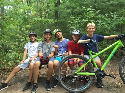 A group of Teen Campers pose for a picture with a bike