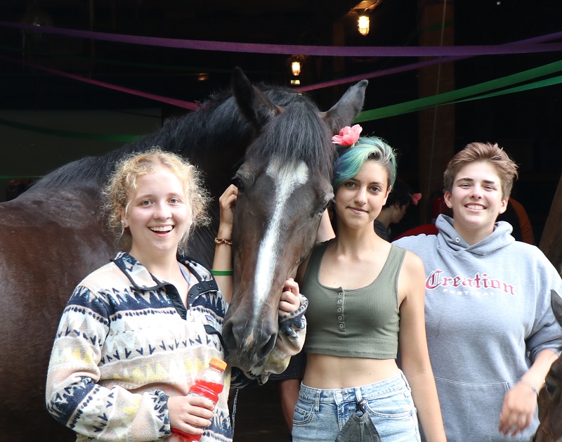 3 female Campers pose for a picture with a horse