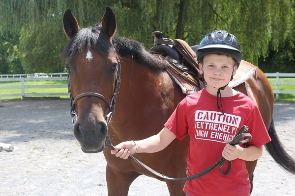 A Teen Camper pose for a picture with a horse