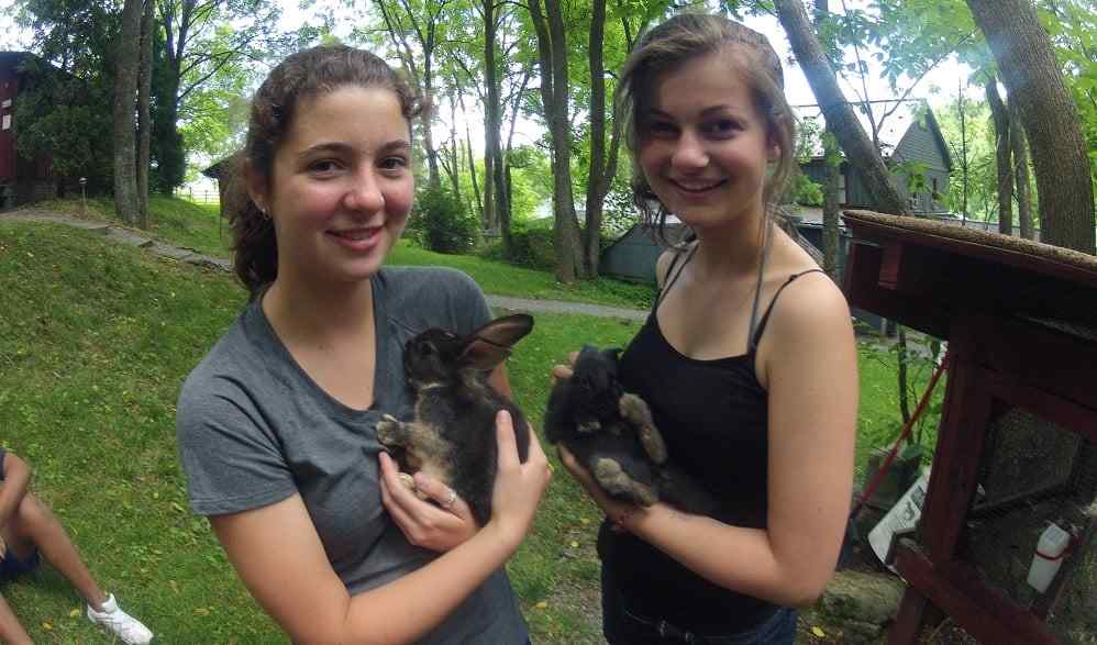 2 female Campers pose for a picture with their pet 