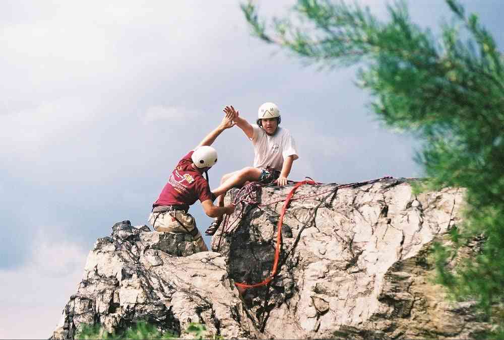 Picture of a counselor assisting a Camper during  a Rock camping session. 